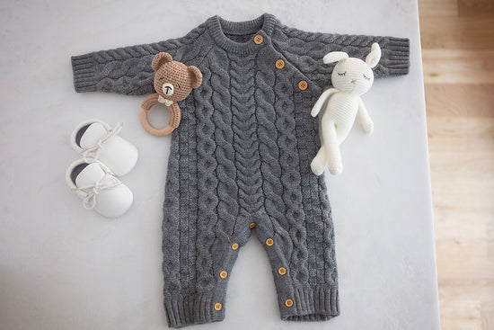 Baby Gift Box items including baby knit romper, bunny stuffed toy, knit bear rattle and infant moccasins